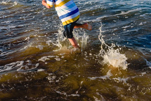 Child running on the sand of the beach splashing with waves in s — Stock Photo, Image