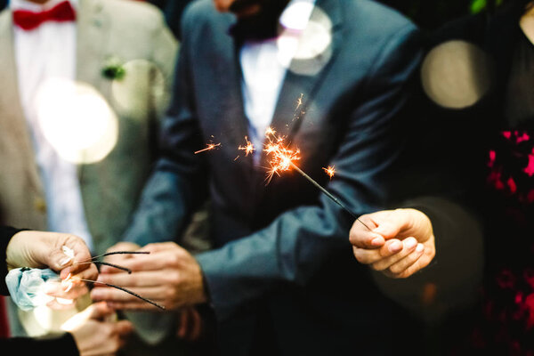 Elegant men holding a flare lit during a party