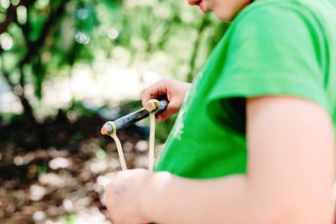 Bir parkta sapanıyla oynayan çocuk özgürlükte eğleniyor