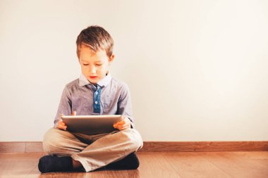 Bir tablet içinde absorbe kullanma katta oturan çocuk.