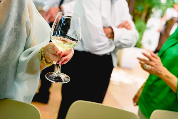 Older woman holding a glass of white wine at her retirement part — Stock Photo, Image