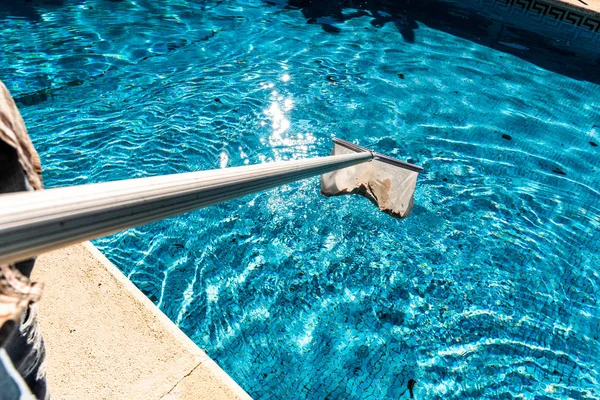 Hombre de mantenimiento usando un rastrillo de skimmer de hoja de red de piscina en verano para —  Fotos de Stock