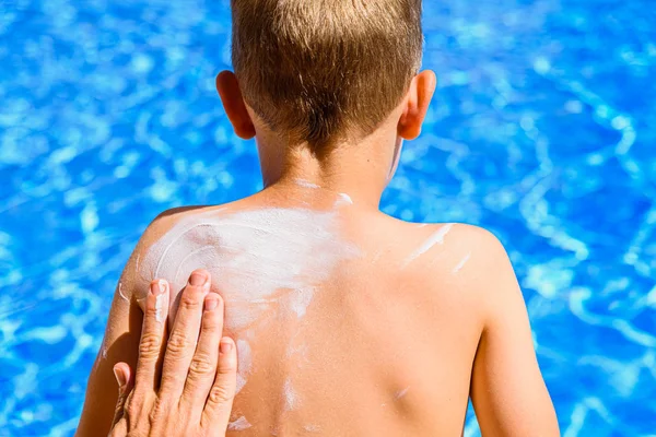 Woman spreads sunscreen on a child's back in summer to avoid sun — Stock Photo, Image
