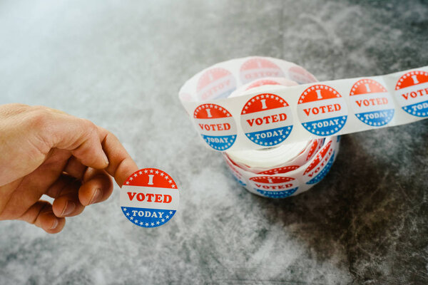 Мужчина держит в руках стикеры сторонников американских выборов
