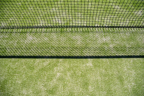 Rede de uma quadra de tênis projetando sua sombra na grama, backgr — Fotografia de Stock