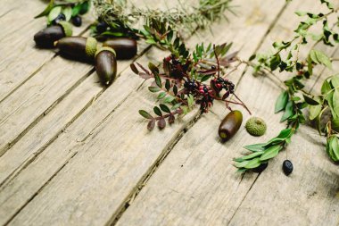 Yaşlı ahşap masa arka plan meşe palamutları, kırmızı çilek ile dekore edilmiştir. 