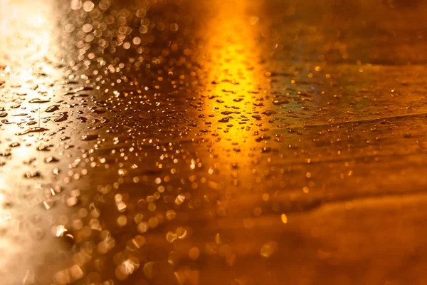 Gotas de chuva em uma mesa de madeira iluminada por luzes de rua um — Fotografia de Stock