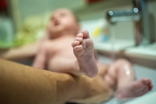 Close-up baby feet bathing helped by his mother. — Stock Photo, Image