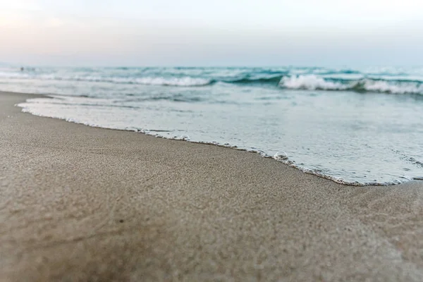 小さな波は穏やかなビーチの海岸に到達し、細かいsを濡らします — ストック写真