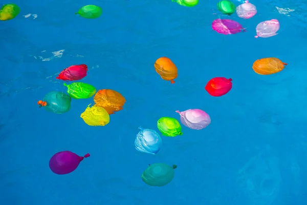 Colorful plastic water balloons floating in a pool to play on va — Stock Photo, Image