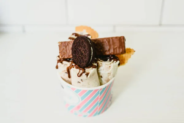Rolled ice cream with chocolate topping and biscuit.