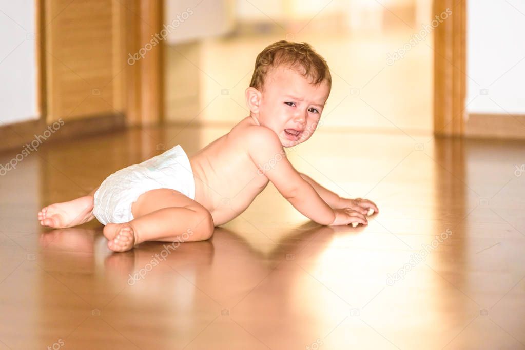 Baby on the floor of his house in diapers, with an angry face an