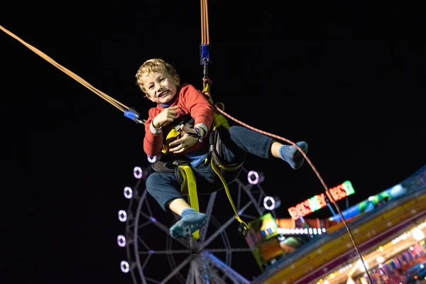 Chico tener un gran tiempo saltando en un trampolín en una feria . —  Fotos de Stock