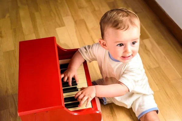 Baby learning to play the piano with a wooden toy instrument, a