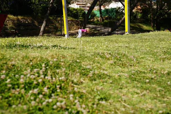 Küçük kız yaz boyunca bir çayır bir salıncak ile oynuyor — Stok fotoğraf