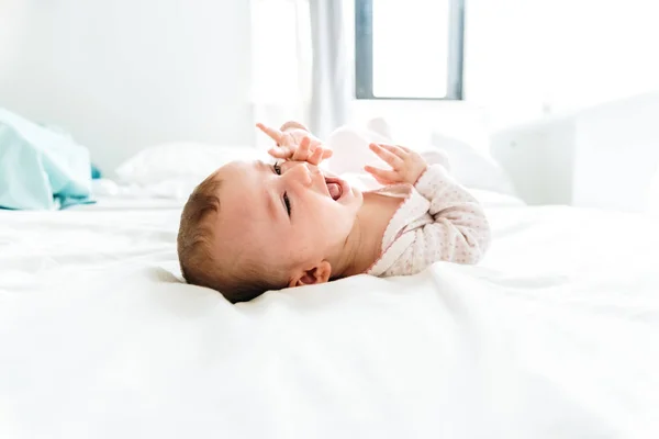 Feliz e sorridente adorável menina de 6 meses deitada em uma cama , — Fotografia de Stock