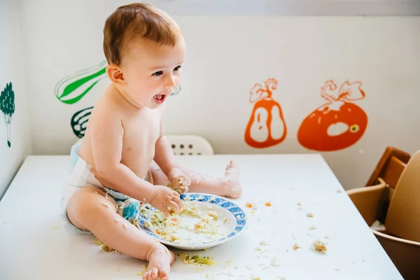 Bebé sonriendo mientras prueba su primer alimento sólido por sí mismo, alte — Foto de Stock