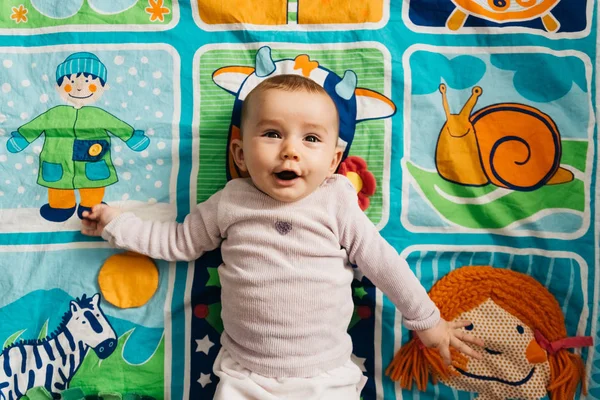 Baby smiling with laughter on a mat of early stimulation. — Stock Photo, Image