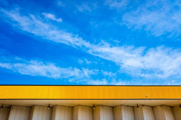 Mooie blauwe hemel met wolken, over een geel bladerdak van een fabriek. — Stockfoto