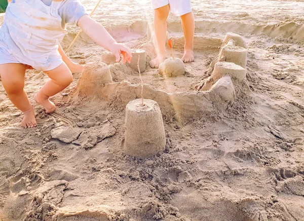 Un niño y un bebé, hermanos, jugando a la construcción del castillo de arena en la b —  Fotos de Stock