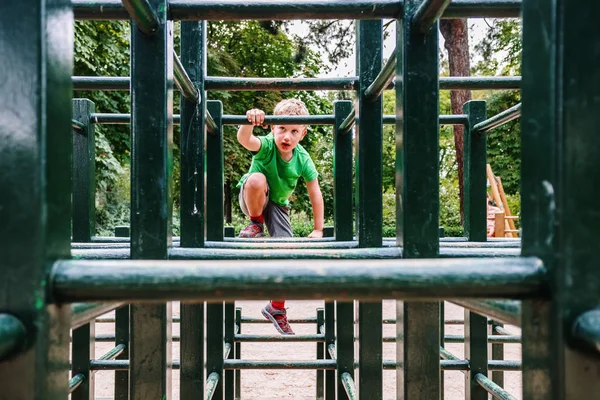 Chłopiec gra w labiryncie drewnianych barów w parku. — Zdjęcie stockowe