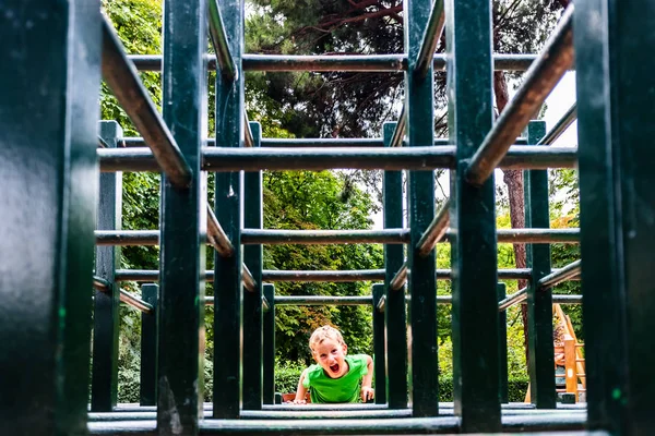 Boy playing in a maze of wooden bars in a park. — Stock Photo, Image