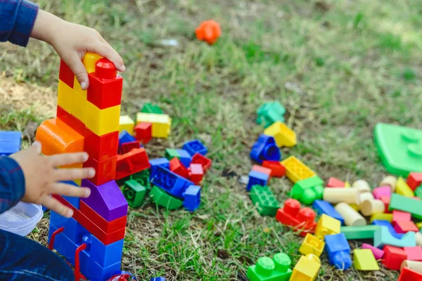 Niño jugando con bloques de colores sentado en el suelo de una ga —  Fotos de Stock