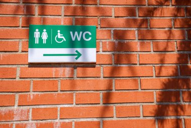 Bir tuğla w üzerinde engelli tuvaletyönünü gösteren plaket