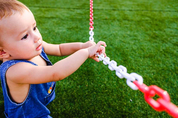 Ребенок играет с цепями в парке на траве . — стоковое фото