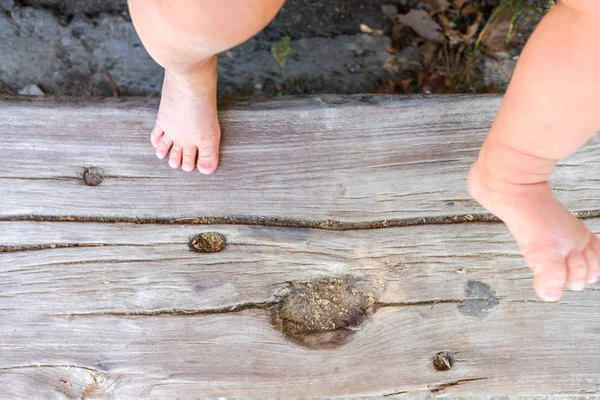 Pés descalços de um bebê apoiados em algumas velhas tábuas de madeira . — Fotografia de Stock