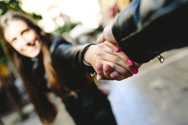 Young woman holding her boyfriend's arm while pulling her away f — Stock Photo, Image
