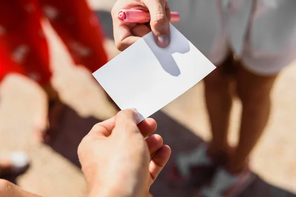 Close-up of hands picking up a white card, in a commercial excha