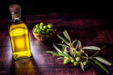 Bir buket çiğ zeytinin yanında sızma zeytinyağı ile şişe 