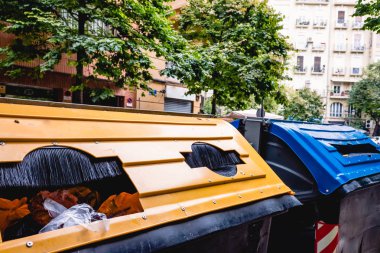 Merkezi bir sokakta büyük kağıt ve plastik geri dönüşüm kutuları.