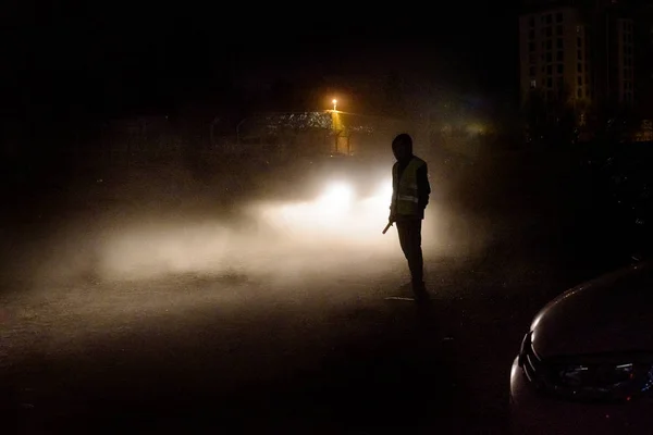 Silhouette des nicht wiederzuerkennenden Mannes beleuchtet durch die Scheinwerfer o — Stockfoto