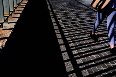 Gün batımında bir şehirde bir sokakta yürüyen yaya tarafından çizgili