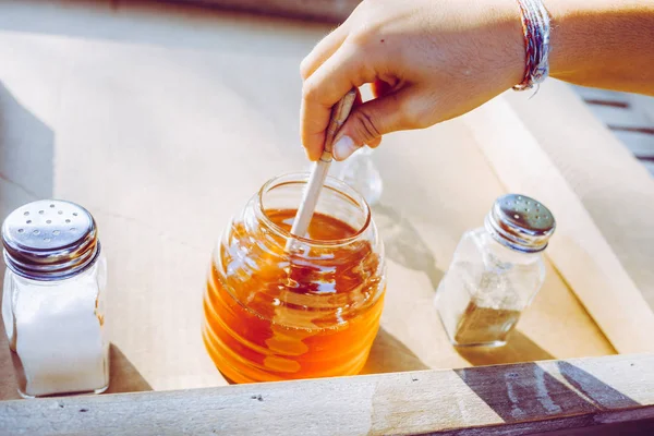 Girl's hand vangen honing uit een glazen pot — Stockfoto