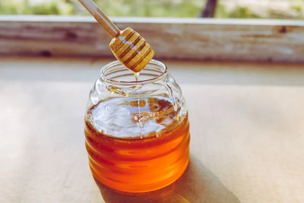 Houten lepel honing Dipper, druipend honing in de pot, unfocu — Stockfoto