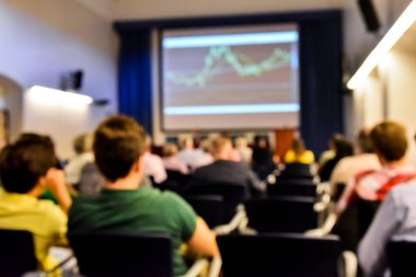Borsa grafikleri ve tanınmayan insanlarla dolu bir ekonomi seminerinin odaklanmış görüntüsü..
