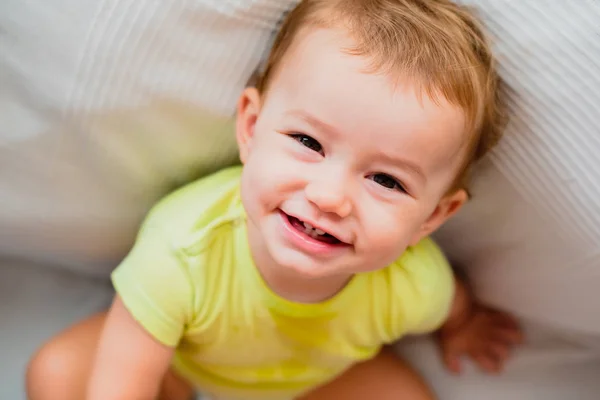 Porträtt av en leende bebis som tittar upp sittande på golvet med — Stockfoto