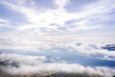 Bir dağın zirvesinin tepesinden bir kış bulutlu gökyüzü sahnesi.