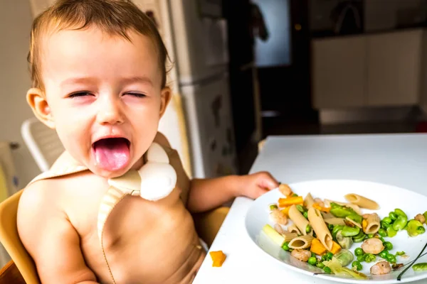 Bebé con cara divertida disfrutando de su comida comiendo con sus manos mak —  Fotos de Stock