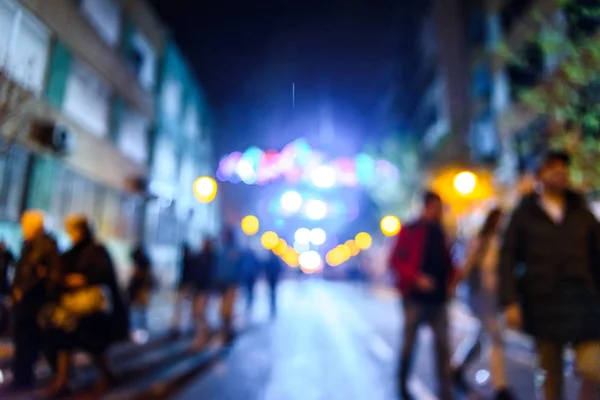 Scena notturna urbana con persone che camminano fuori fuoco con colori — Foto Stock