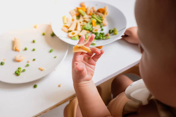 One-year-old baby eats the food from his plate directly with his Stock Photo