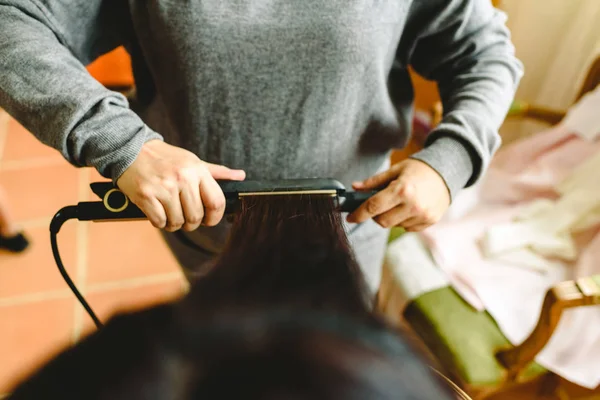 Hairdresser smoothing a woman's hair with a hair straightener. — Stock Photo, Image