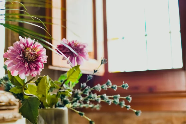 En vas med rosa blommor pryder ingången till ett hus, bredvid — Stockfoto