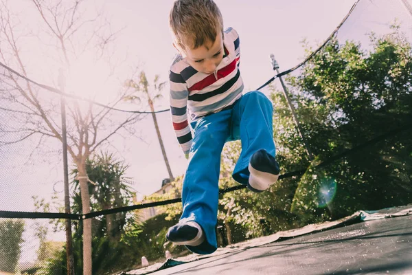 5-летний мальчик прыгает на батуте наслаждаясь своей энергией, лицом — стоковое фото