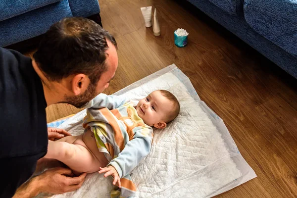 Affectionate father playing with his baby while he changes the d — Stock Photo, Image