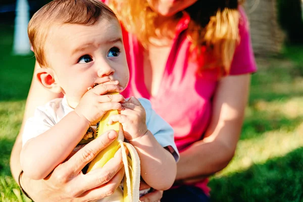 Bebé en brazos de su madre aprendiendo a comer alimentos sólidos como la f cruda — Foto de Stock