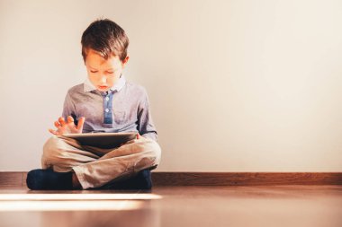 Bir tablet içinde absorbe kullanma katta oturan çocuk.